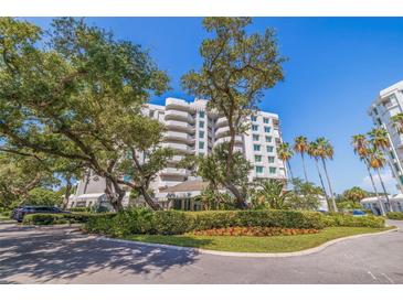 Luxury condo building with lush landscaping and palm trees at 1 Seaside Ln # 104, Belleair, FL 33756