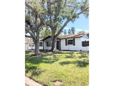 Charming single-story home features mature trees, neutral paint, dark shutters, and a cozy, inviting facade at 1800 Montana Ne Ave, St Petersburg, FL 33703