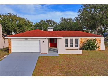 Single-story house with red tile roof, white garage door, and red front door at 2502 Indigo Dr, Dunedin, FL 34698