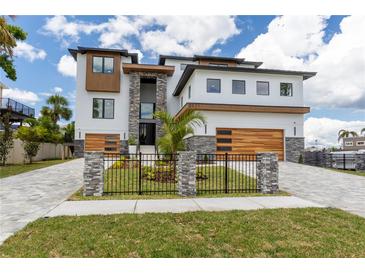 Modern home with stone accents, a fenced yard, a two-car garage, and meticulous landscaping on a sunny day at 2121 Bayou Grande Ne Blvd, St Petersburg, FL 33703