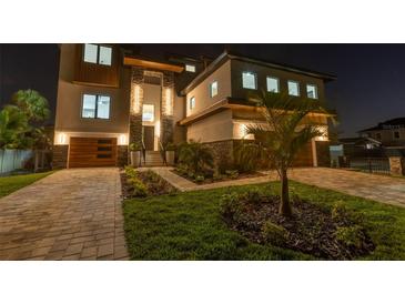 Stunning, modern home with stone accents, wood garage doors, manicured landscaping and welcoming exterior lighting at 2121 Bayou Grande Ne Blvd, St Petersburg, FL 33703