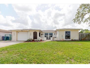 Charming home with a well-maintained lawn, decorative front door, and attached one-car garage at 1172 Chelsea Ln, Holiday, FL 34691