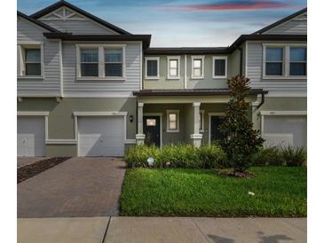 Charming townhome featuring a well-maintained lawn, brick driveway, and an inviting covered front porch at 21811 Lyonia Ln, Land O Lakes, FL 34637