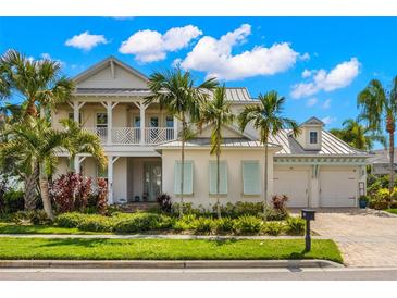 Two-story home with light-colored siding, a metal roof, and a covered porch at 709 Manns Harbor Dr, Apollo Beach, FL 33572