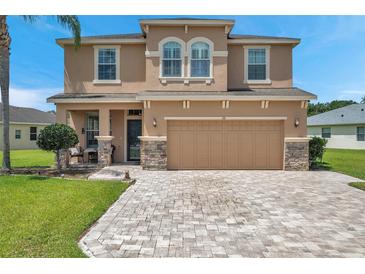 Two-story house with tan exterior, stone accents, and paver driveway at 116 Caladium Ct, Bradenton, FL 34212
