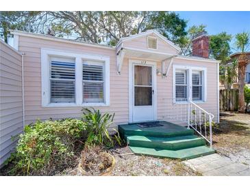 Charming light pink bungalow with green steps, white shutters, and well-maintained landscaping at 113 93Rd Ave, Treasure Island, FL 33706