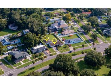 A perfect aerial view of a beautiful landscaped home with yellow markings and surrounding mature trees at 102 Shore W Dr, Oldsmar, FL 34677