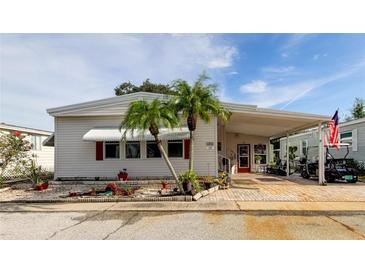 Single-wide mobile home with covered carport and tropical landscaping at 192 Blue Marlin Dr, Oldsmar, FL 34677