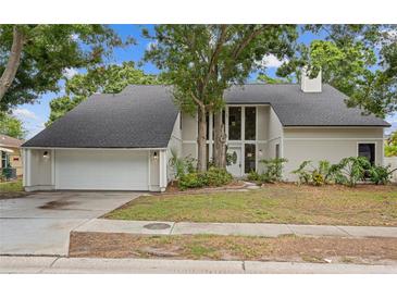 Charming home with manicured lawn, mature trees, and large window accents for natural light at 5841 Bay Pines Lakes Blvd, St Petersburg, FL 33708