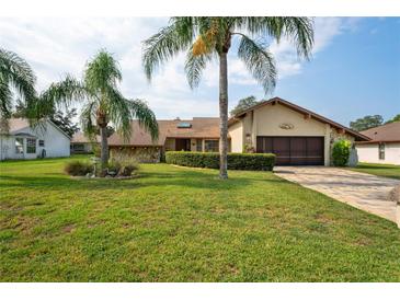 House exterior featuring a stone facade and landscaped lawn at 7988 Ravenwood Cv, Spring Hill, FL 34606