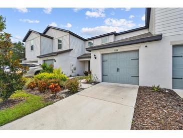 Modern townhouse with a light gray garage door and landscaping at 5228 New Friendship Pl, Tampa, FL 33619