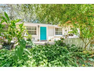 Charming home with teal front door, surrounded by lush landscaping at 37427 Southside Dr, Zephyrhills, FL 33541