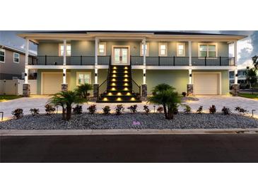 Two-story house with lighted staircase and landscaping at 83 Palm Blvd, Dunedin, FL 34698