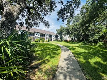 Paved walkway winds through lush landscaping towards condo building at 400 N Bayshore Blvd # 104, Clearwater, FL 33759