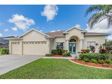 House exterior with three-car garage and manicured landscaping at 22531 Eagles Watch Dr, Land O Lakes, FL 34639