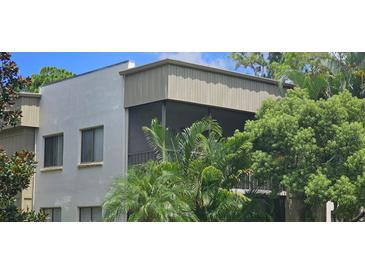 Exterior view of a condo building with balconies and lush tropical landscaping at 3300 Fox Chase N Cir # 231, Palm Harbor, FL 34683