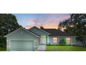 Newly constructed light teal home with a two-car garage and nicely landscaped lawn at 105 Dartmouth Rd, Venice, FL 34293