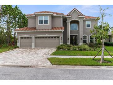 Stunning two-story home with red tile roof, three-car garage and brick-paved driveway at 32924 Estate Garden Dr, Wesley Chapel, FL 33545