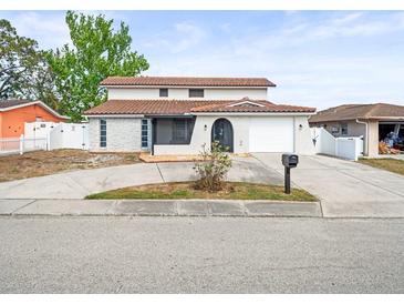 Two-story home featuring a red tiled roof, stucco walls, and a well-manicured front yard at 9100 Suffolk Ln, Port Richey, FL 34668