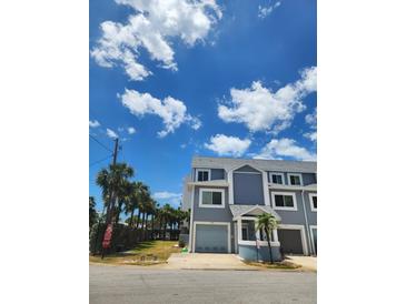 A light blue two-story townhouse with an attached garage on a sunny day at 900 Harbour House Dr, Indian Rocks Beach, FL 33785