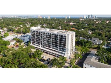 Stunning aerial view of a high-rise condominium building in a lush, green neighborhood near downtown with a water view in the distance at 3211 W Swann Ave # 808, Tampa, FL 33609