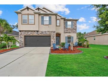 Charming two-story home with a well-manicured lawn, stone accents, and a welcoming front porch at 7114 Mill Hopper Ct, Palmetto, FL 34221