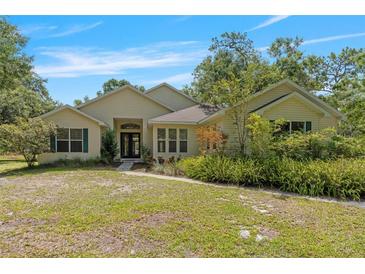 Charming single-story home with a well-manicured lawn and lush landscaping at 11933 Pasco Trails Blvd, Spring Hill, FL 34610