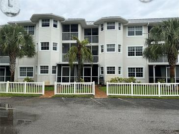 Two-story condo building with white exterior, screened balconies, and a white picket fence at 2077 Wetland Pt # 1202, Lutz, FL 33558