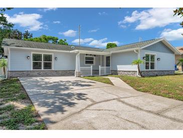 Newly renovated light blue house with stone accents and a landscaped yard at 302 Leafwood Rd, Tarpon Springs, FL 34689