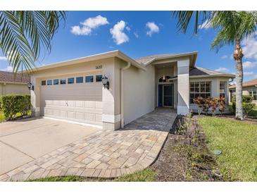 Single story home with tan exterior, light colored garage door and a paved walkway at 1633 Arbor Knoll Loop, Trinity, FL 34655