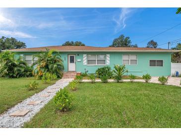 Light teal single story home with a well manicured lawn and walkway at 800 61St N St, St Petersburg, FL 33710