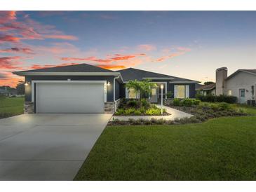 Exterior of a single-story home with a gray garage door at dusk at 5406 Boxtree Ct, Dade City, FL 33523