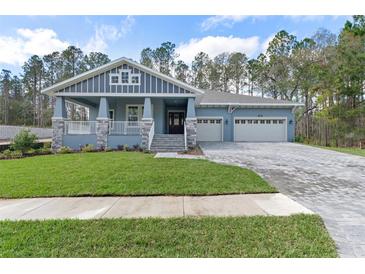 Charming single-Gathering home showcasing a craftsman style exterior, well-manicured lawn, and a spacious three car garage at 3898 Southern Valley Loop, Brooksville, FL 34601