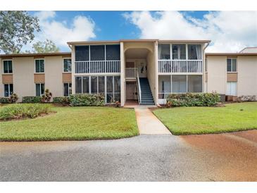 Exterior of a two-story condo building with a walkway and landscaped lawn at 12119 Sunny Glen Ln # H1, Hudson, FL 34669