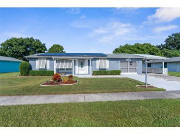 Ranch-style home with solar panels, carport, and well-manicured lawn at 3391 Lambert Ave, Spring Hill, FL 34608