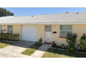 Front view of a light-yellow single-story home with a white garage door at 4930 Filner St # 4930, New Port Richey, FL 34652