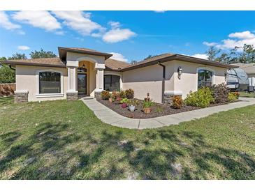 Tan house with landscaping and walkway at 12233 Pitcairn St, Brooksville, FL 34613