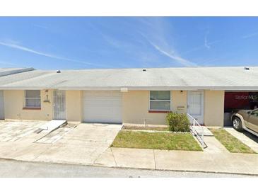 Tan, two-unit building with garage doors and landscaping at 4933 Filner St # 4933, New Port Richey, FL 34652