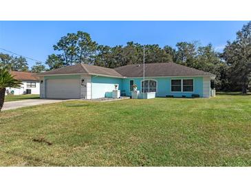 Charming light blue house with a spacious lawn and attached garage at 3018 Greynolds Ave, Spring Hill, FL 34608
