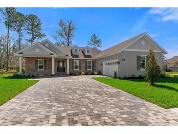 Charming single-story home featuring a brick facade, gray shutters, and a patterned brick driveway at 19364 Sheltered Hill Dr, Brooksville, FL 34601