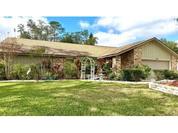 Charming brick home featuring a well-manicured lawn, mature landscaping, and decorative fountain at 6206 Soaring Ave, Temple Terrace, FL 33617