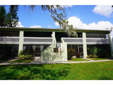 Front view of a light green two-story building with white railings and landscaping at 1775 Cupecoy Cir # O4, Lutz, FL 33558