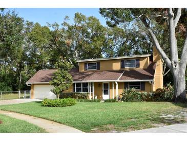 Tan house with brown roof, attached garage, and spacious lawn at 15473 Darien Way, Clearwater, FL 33764