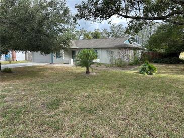 House with a large front yard, landscaping, and driveway at 8353 Forest Oaks Blvd, Spring Hill, FL 34606