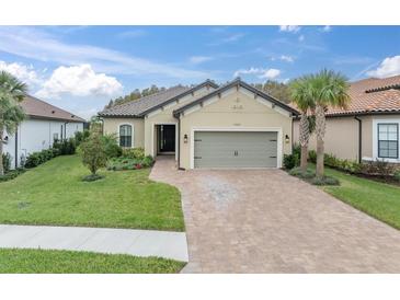 Tan house with gray garage door and landscaping; a paved driveway leads to the home at 10693 Calluna Dr, Odessa, FL 33556