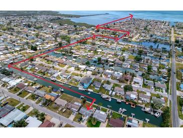Aerial view of waterfront homes with boat docks and canal access in a coastal community marked with red path to open water at 13639 Frances Ave, Hudson, FL 34667