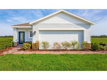 One-story home with light blue exterior, brick walkway, and two-car garage at 2595 Scenic Park Loop, Wimauma, FL 33598