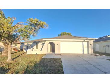 White house with a two-car garage and mature landscaping at 1304 Greenlea Dr, Holiday, FL 34691