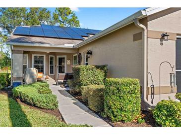 Inviting walkway to front entrance, featuring landscaping and solar panels at 1400 Summerwood Ct, Spring Hill, FL 34606