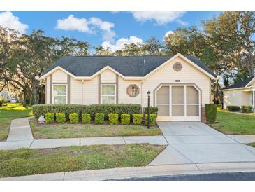 One-story house with beige siding, attached garage, and well-manicured landscaping at 4982 Bostonian Loop, New Port Richey, FL 34655